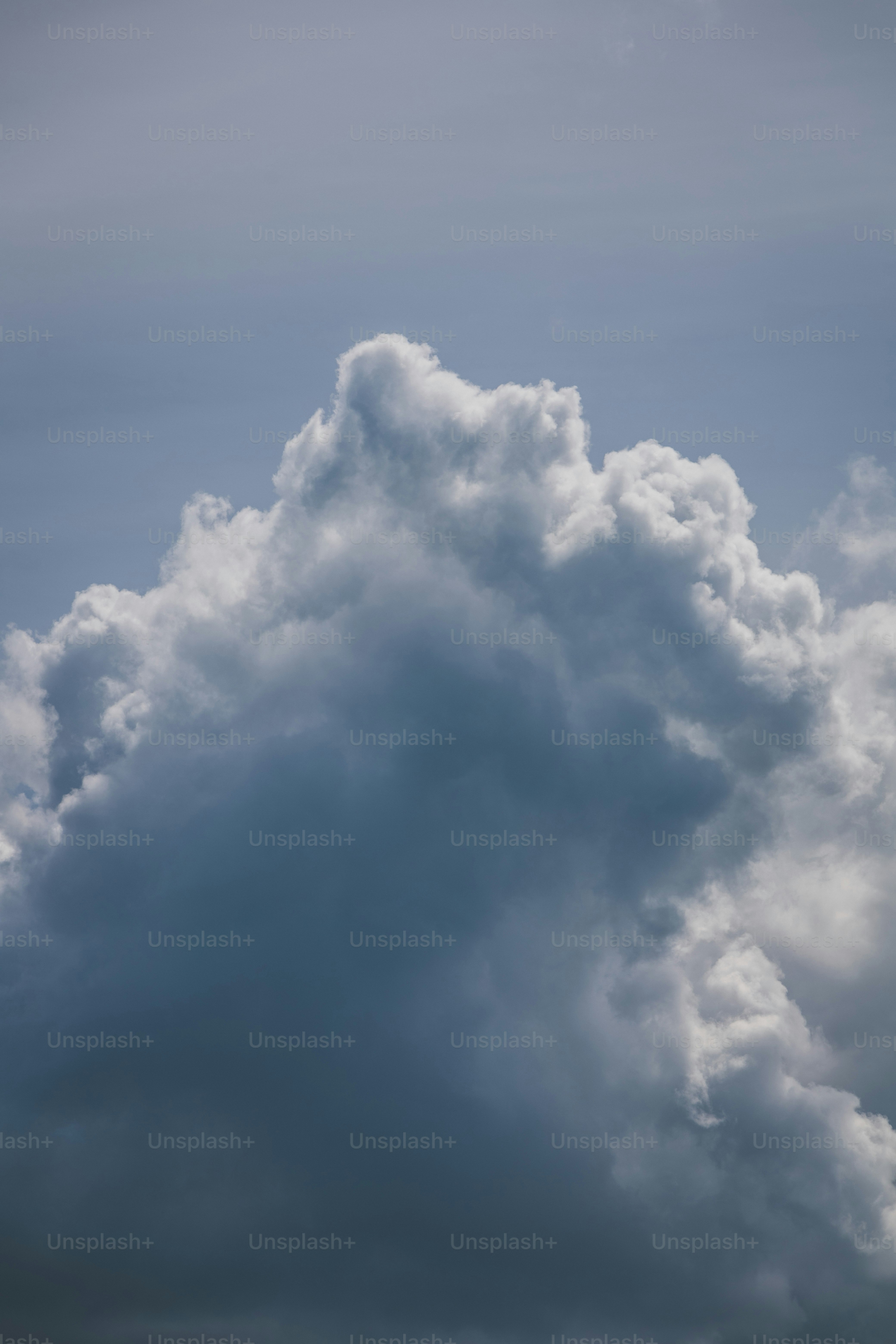 a plane flying through a cloudy blue sky