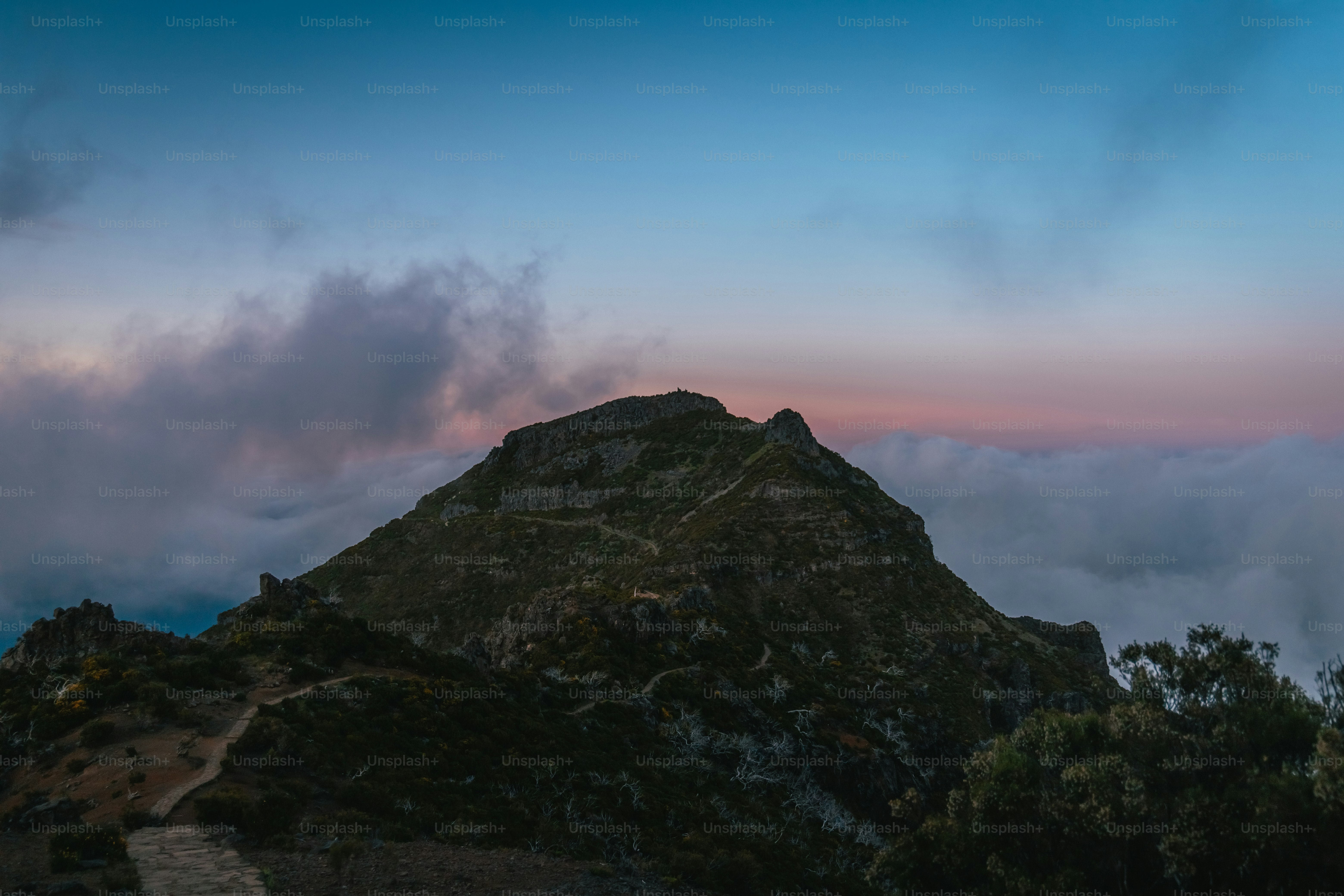 a mountain covered in clouds at sunset