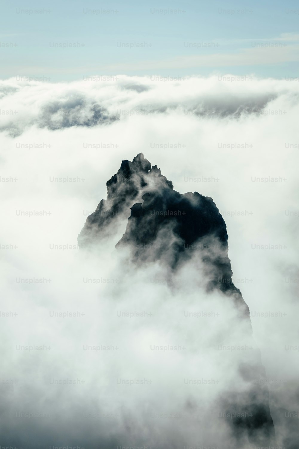 a mountain surrounded by clouds in the sky
