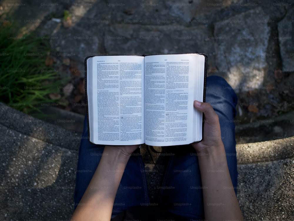 Una persona sentada en el suelo leyendo un libro