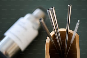 a cup filled with metal straws next to a bottle