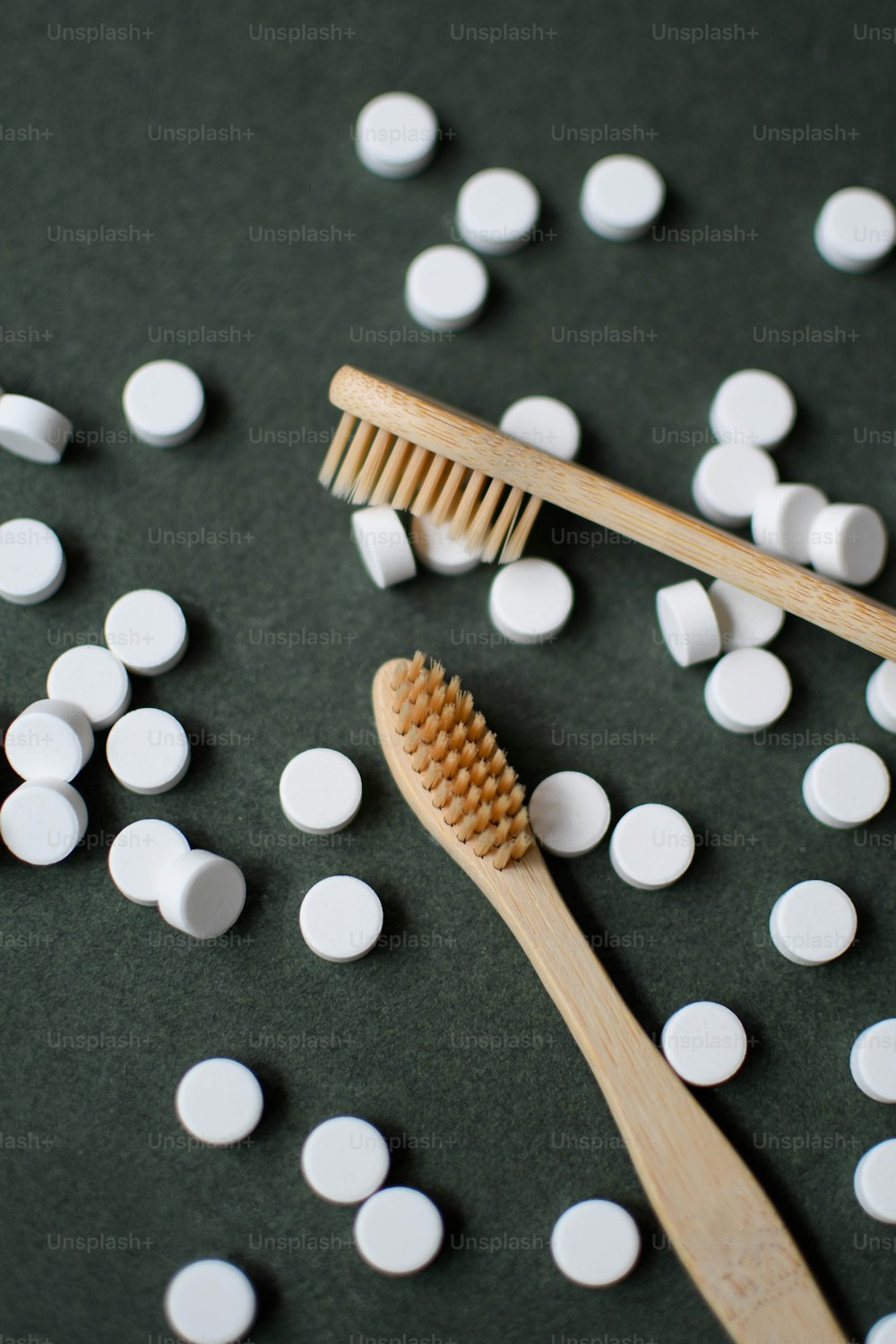 une brosse à dents en bois posée sur une pile de pilules blanches