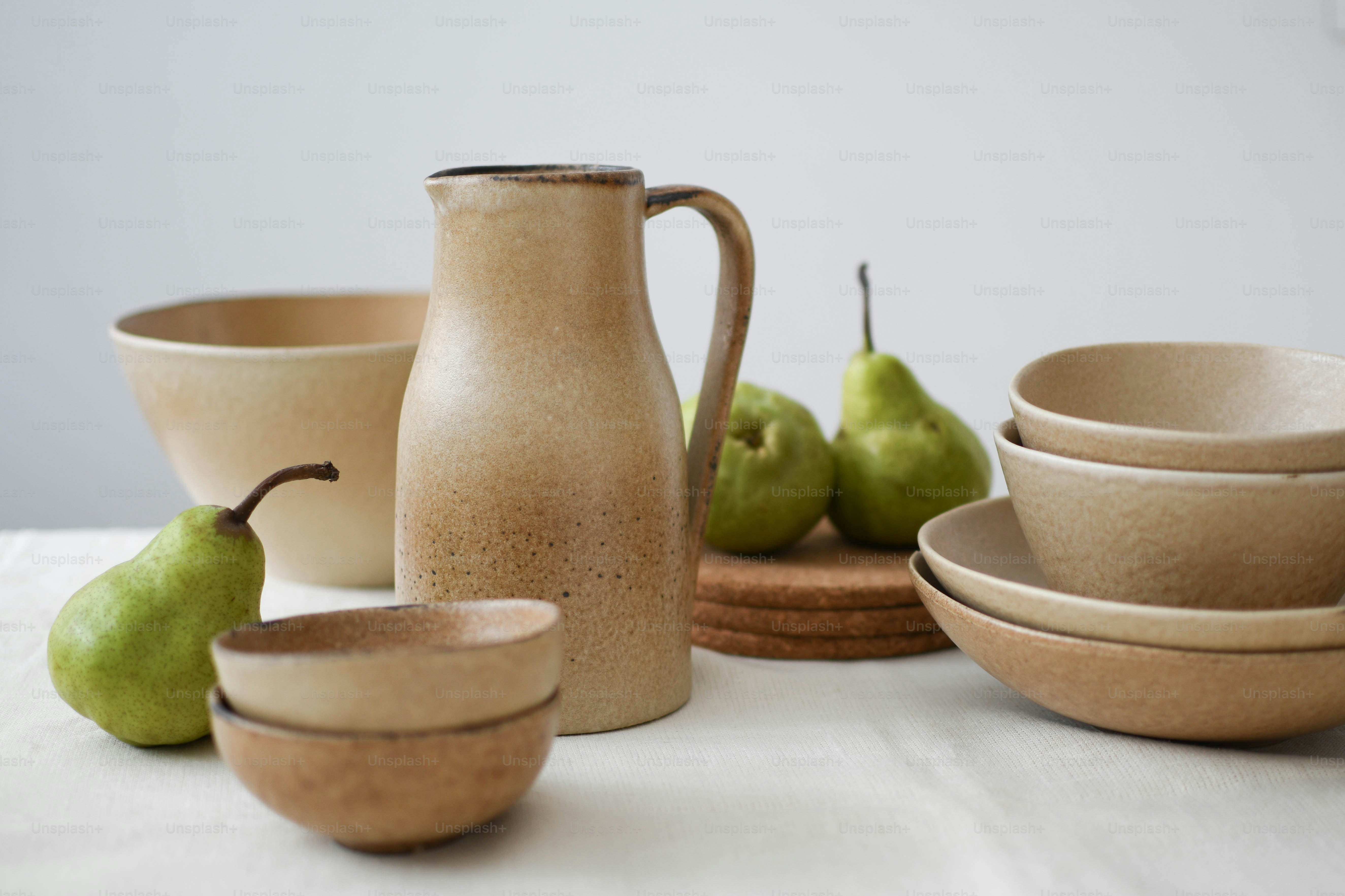 a table topped with bowls and pears next to a pitcher