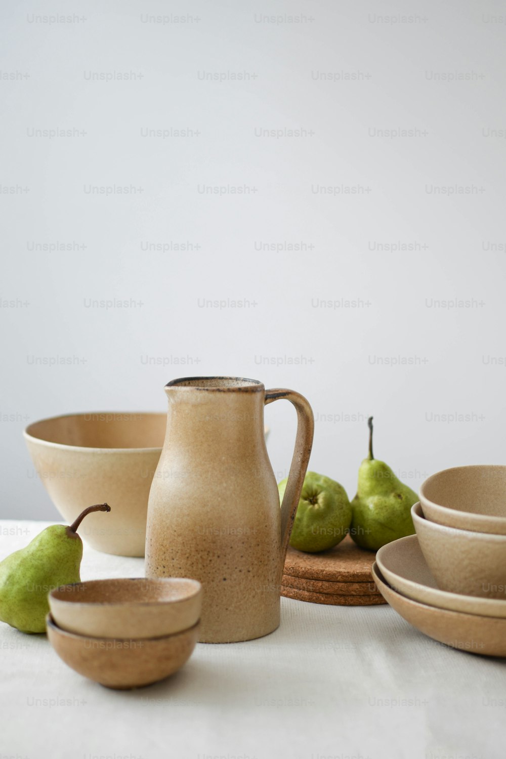 a white table topped with bowls and pears