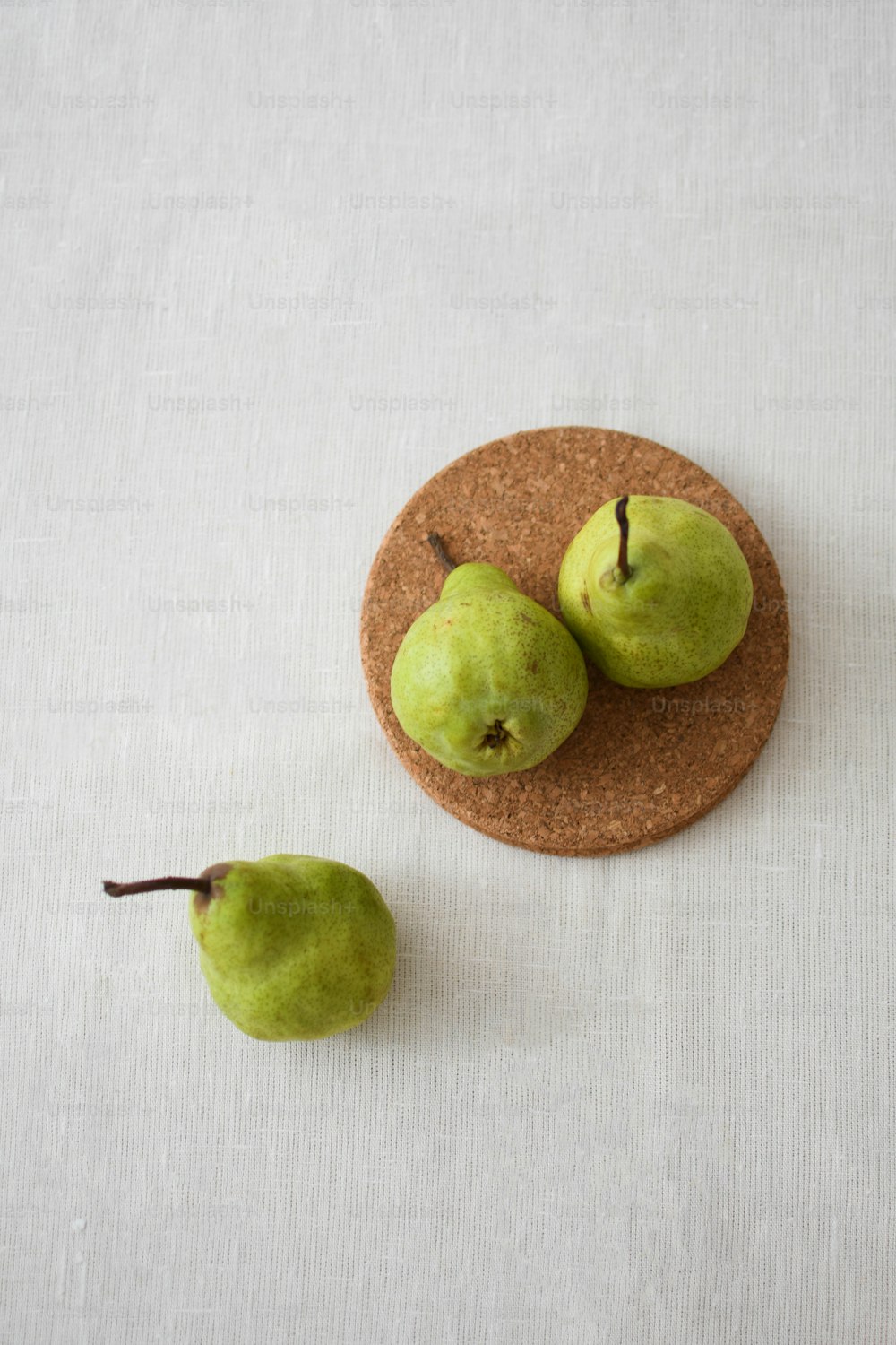 two green pears on a cork coaster