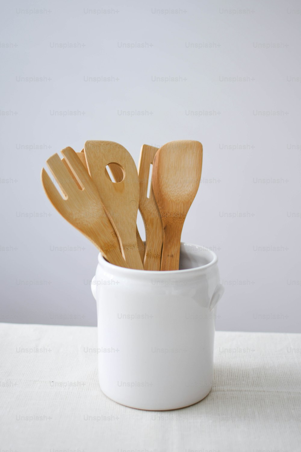 a white cup filled with wooden utensils on top of a table