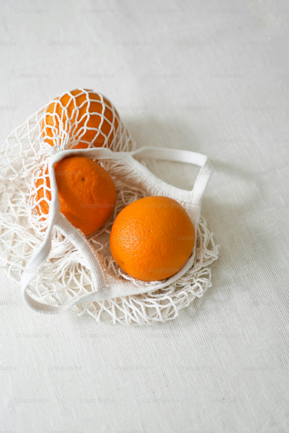 白いテーブルクロスの上に座っている2つのオレンジ