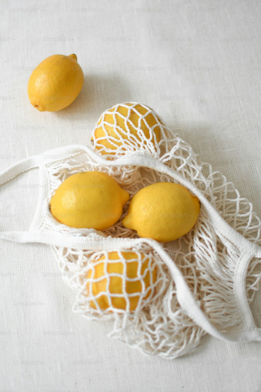 Tres limones en una bolsa de red sobre una mesa