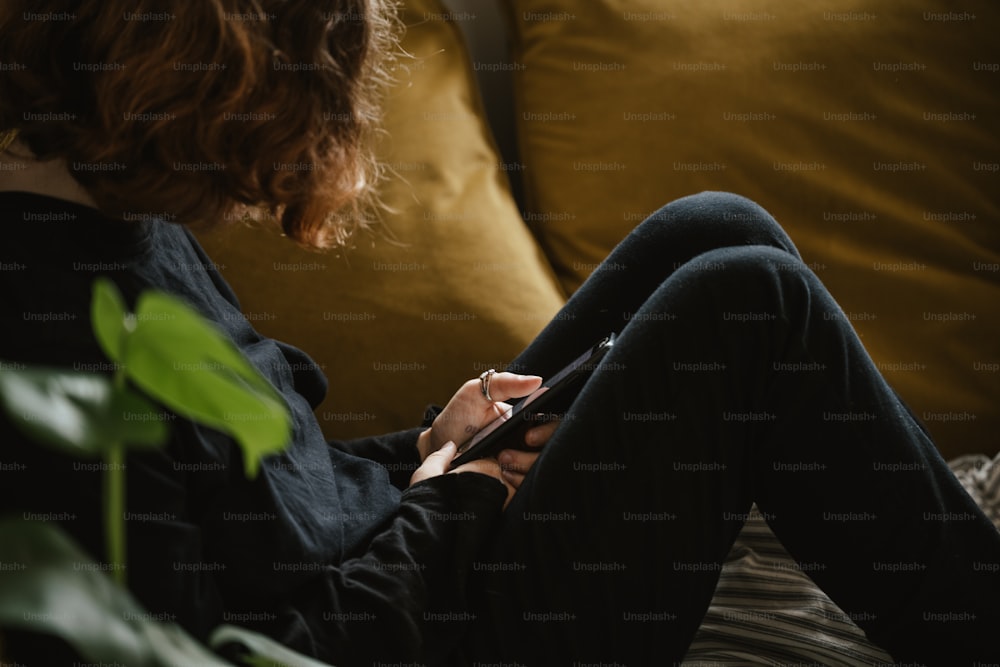 a woman sitting on a couch looking at her cell phone