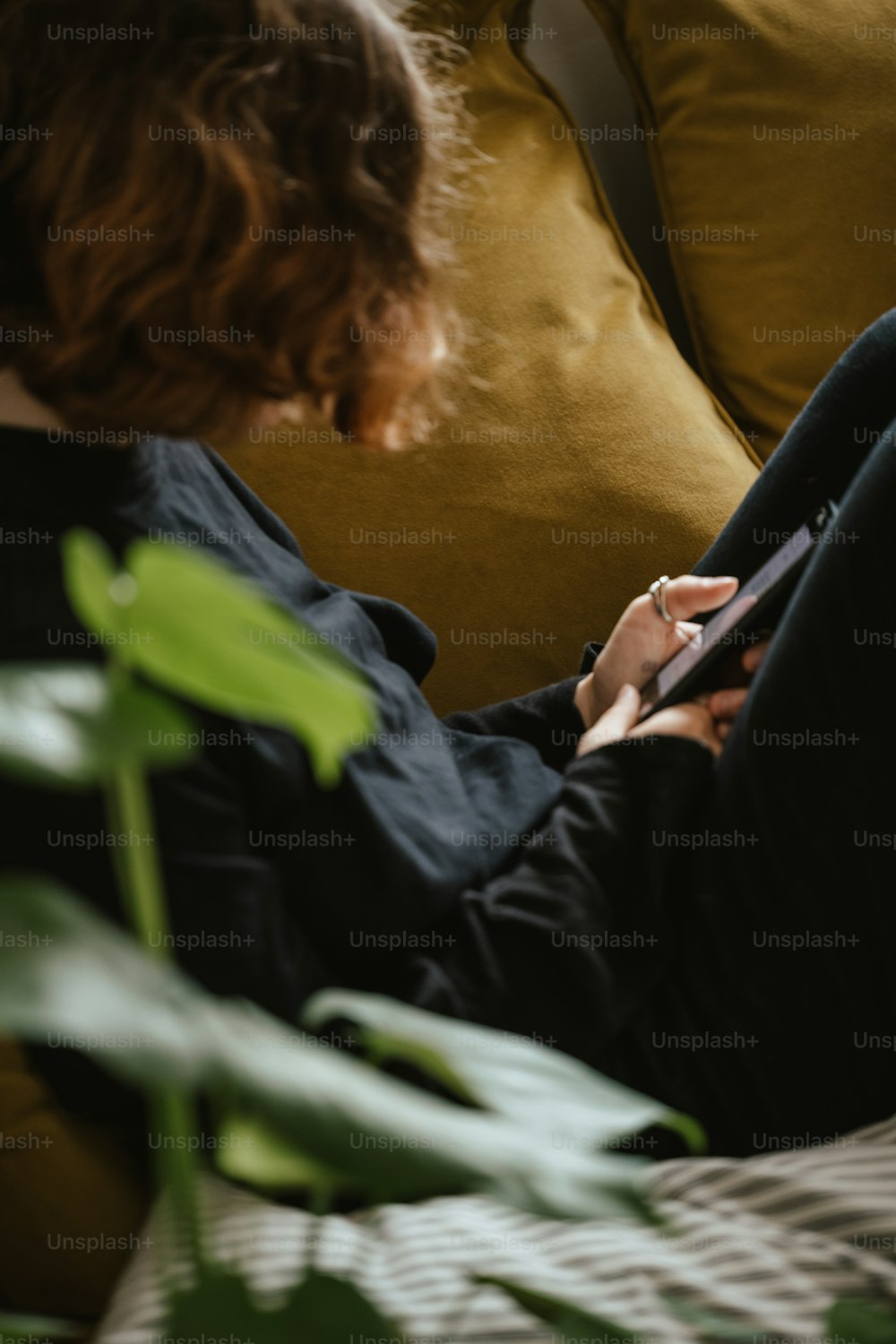 a woman sitting on a couch looking at her cell phone