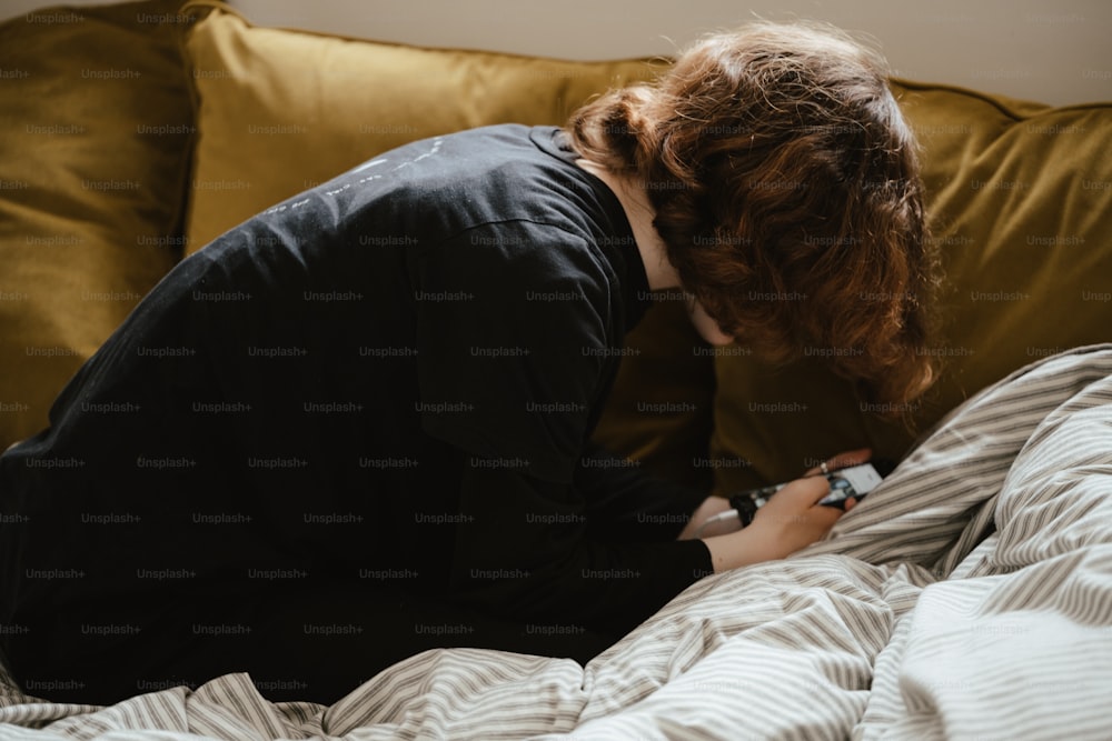 uma mulher sentada em uma cama olhando para um celular