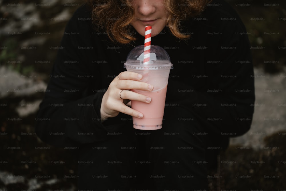 a woman holding a drink with a straw in her hand