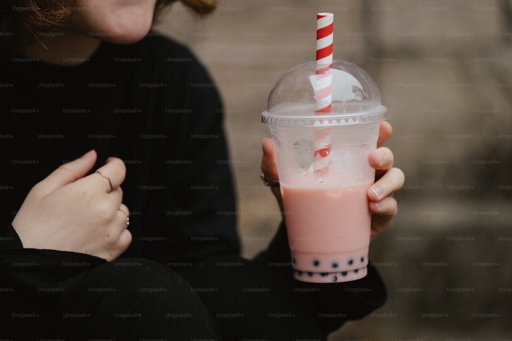 a woman holding a drink with a straw in her hand