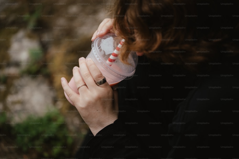 a woman holding a cup with a straw in it