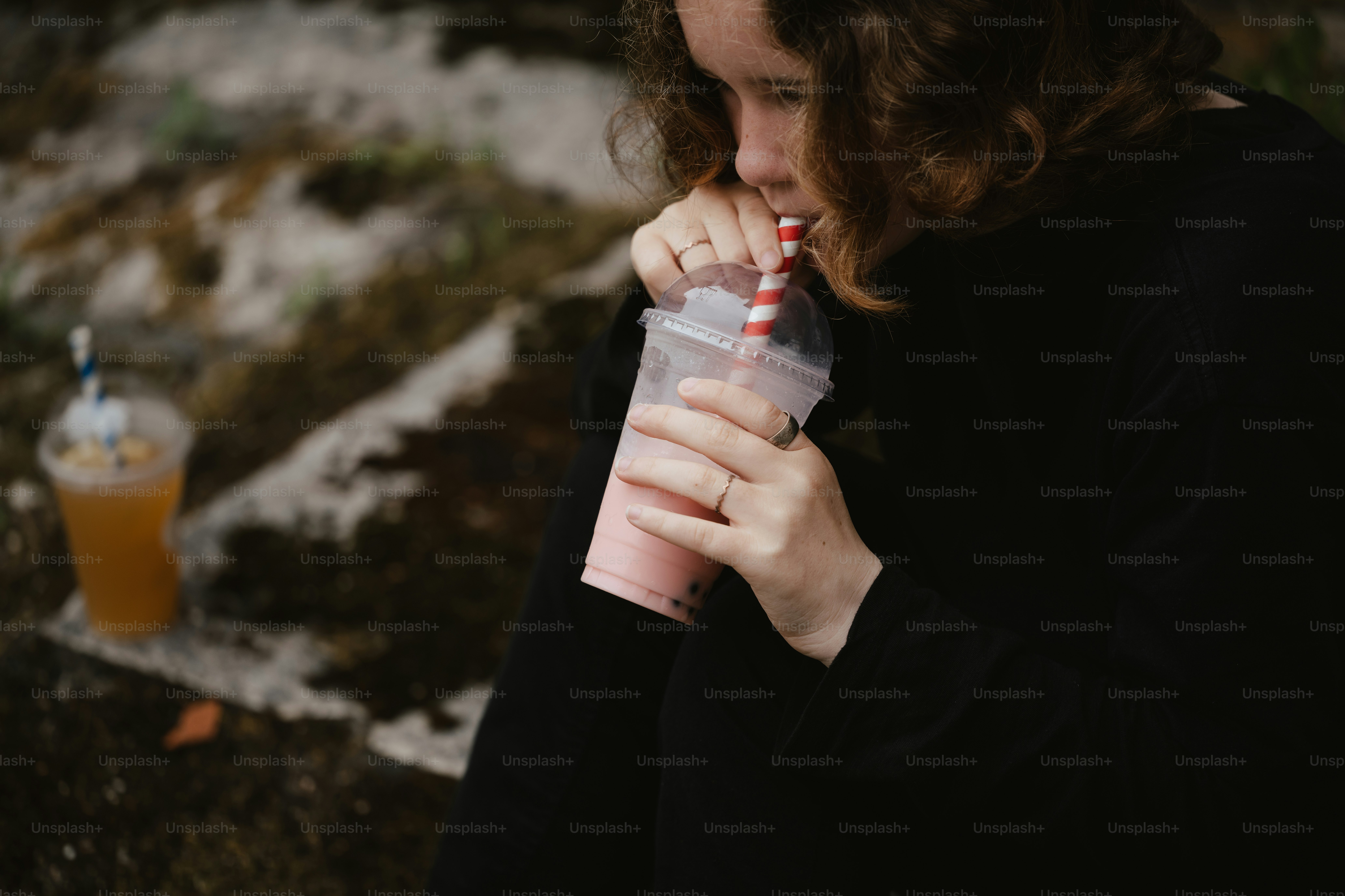 Una mujer está bebiendo un batido afuera