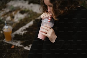 a woman is drinking a smoothie outside