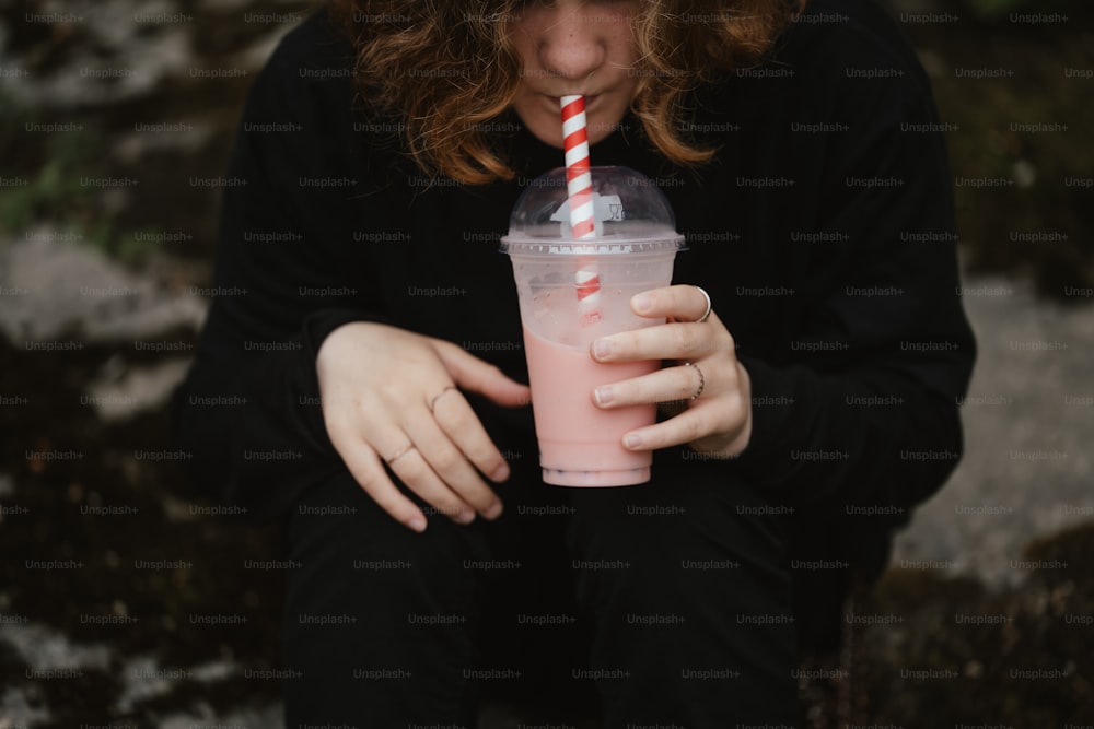 a woman holding a drink with a straw in her hand