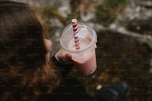 a person holding a drink with a straw in it
