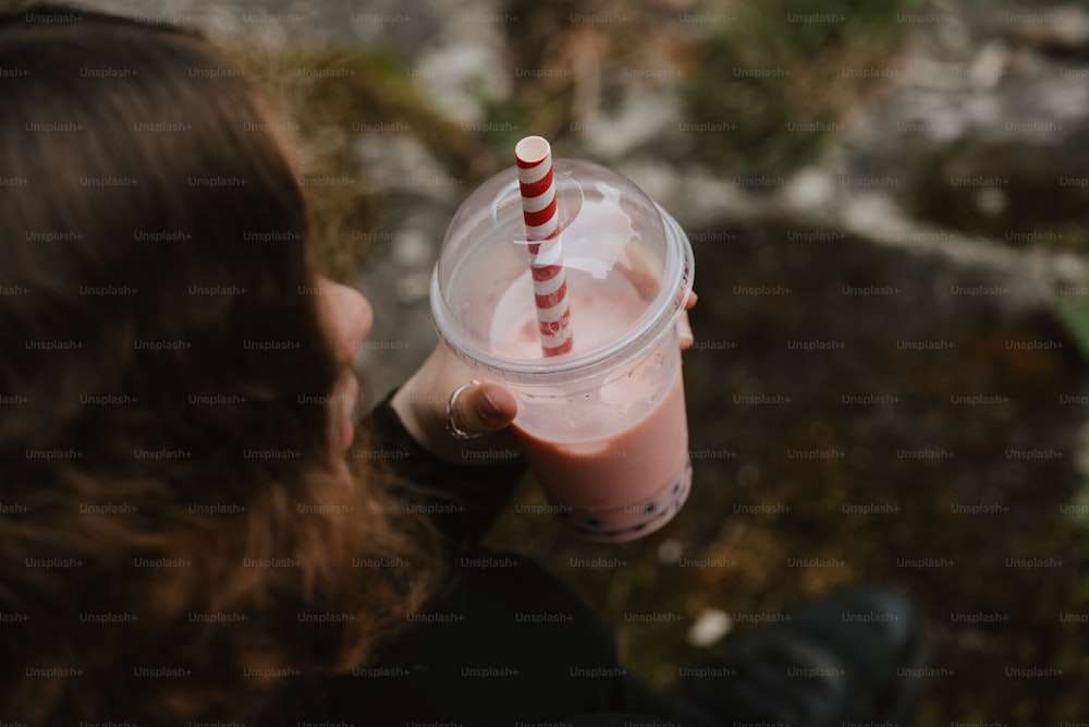 a person holding a drink with a straw in it