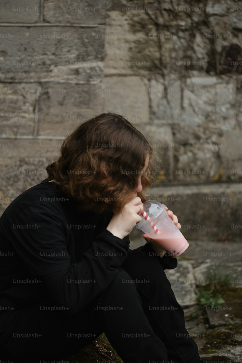 una donna seduta per terra che beve da una tazza