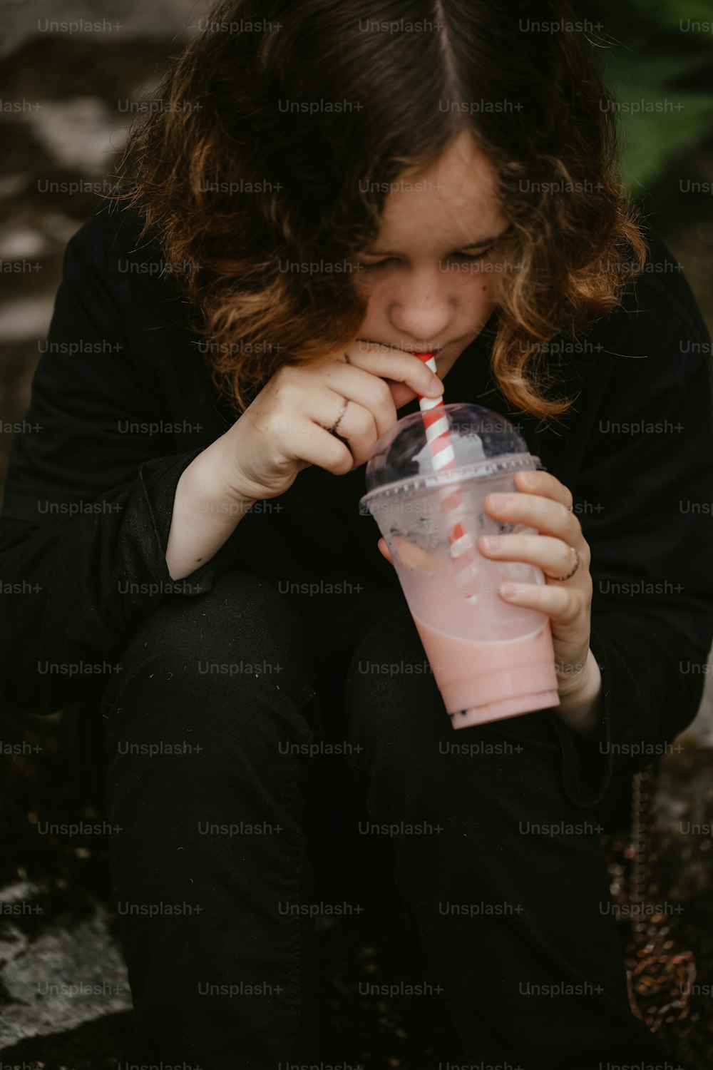 地面に座ってピンクのカップから飲む女性