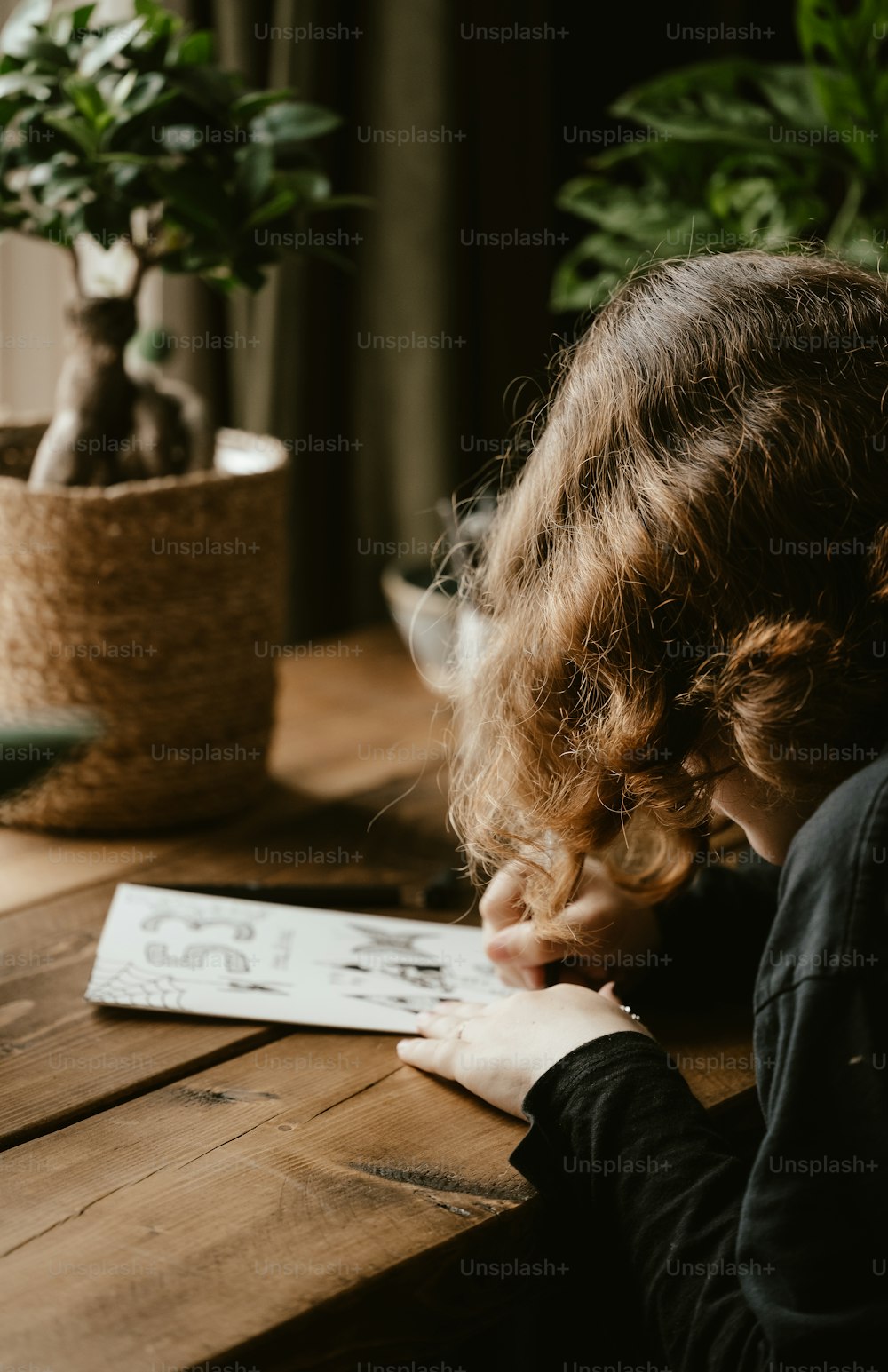 a woman sitting at a table writing on a piece of paper