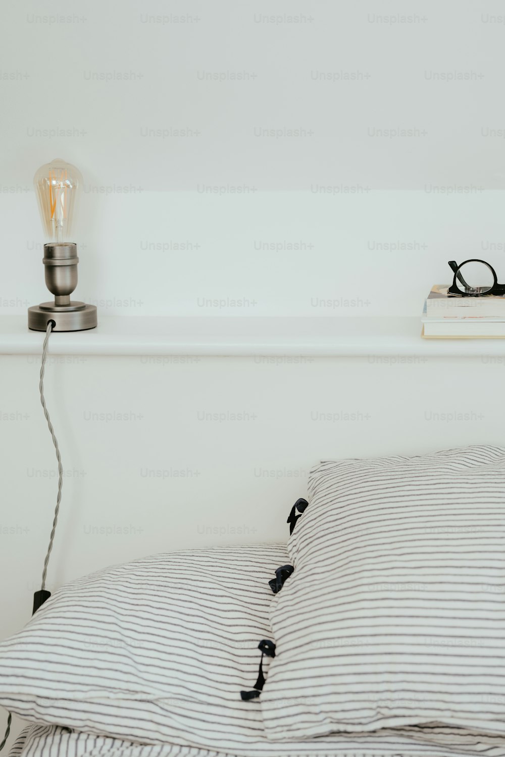 a bed with a striped comforter and a light bulb