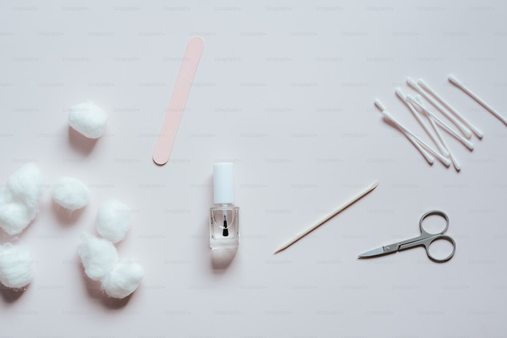 a pair of scissors, cotton balls, and cotton swabs on a white