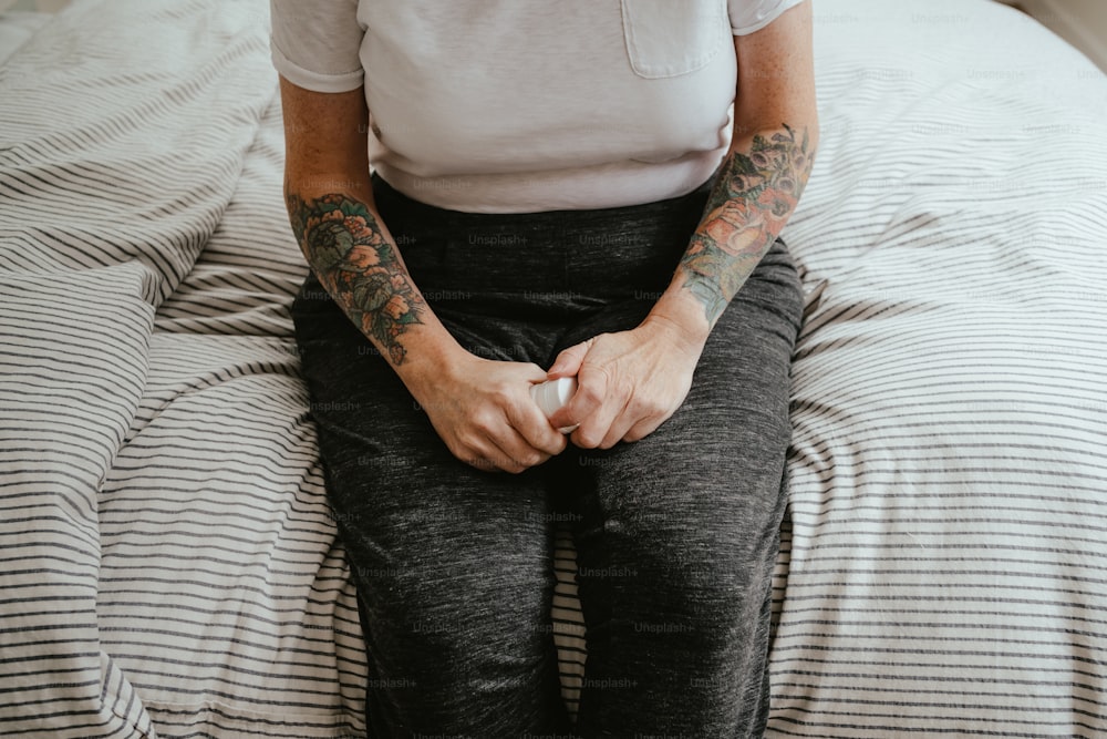 a person with tattoos sitting on a bed