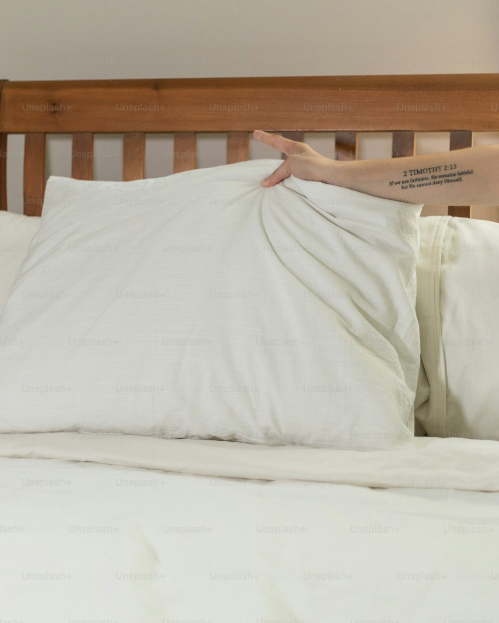 a person reaching for a pillow on a bed