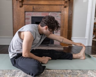 a man sitting on a yoga mat in front of a fireplace