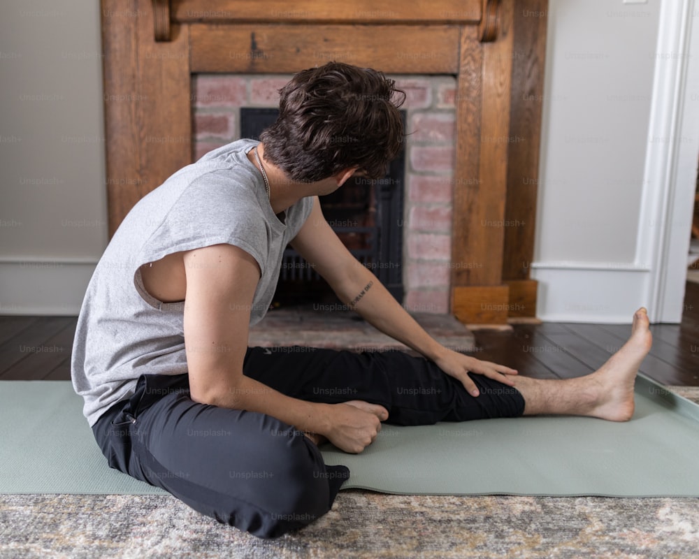 a man sitting on a yoga mat in front of a fireplace