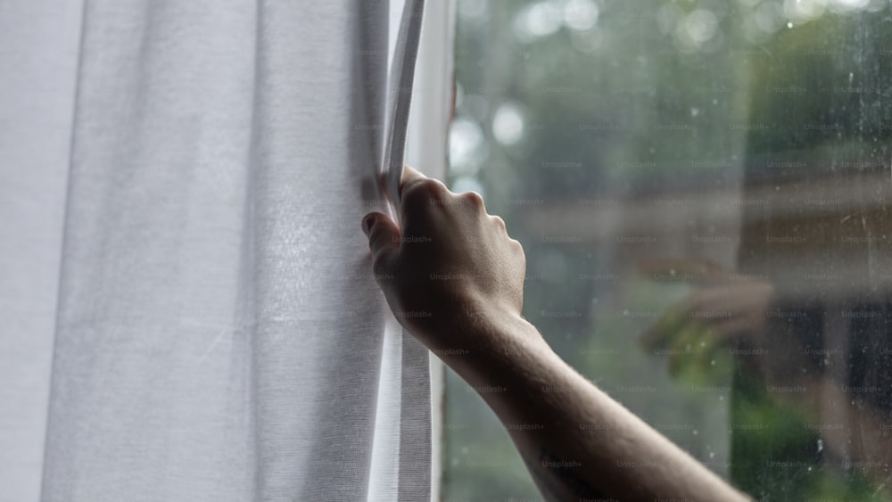 Die Hand einer Person, die aus einem Fenster greift