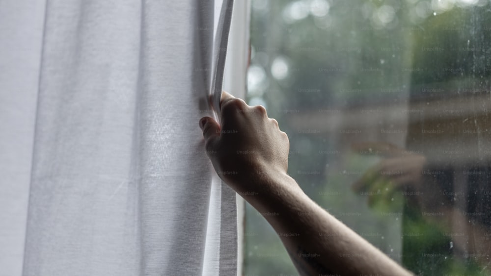 a person's hand reaching out of a window