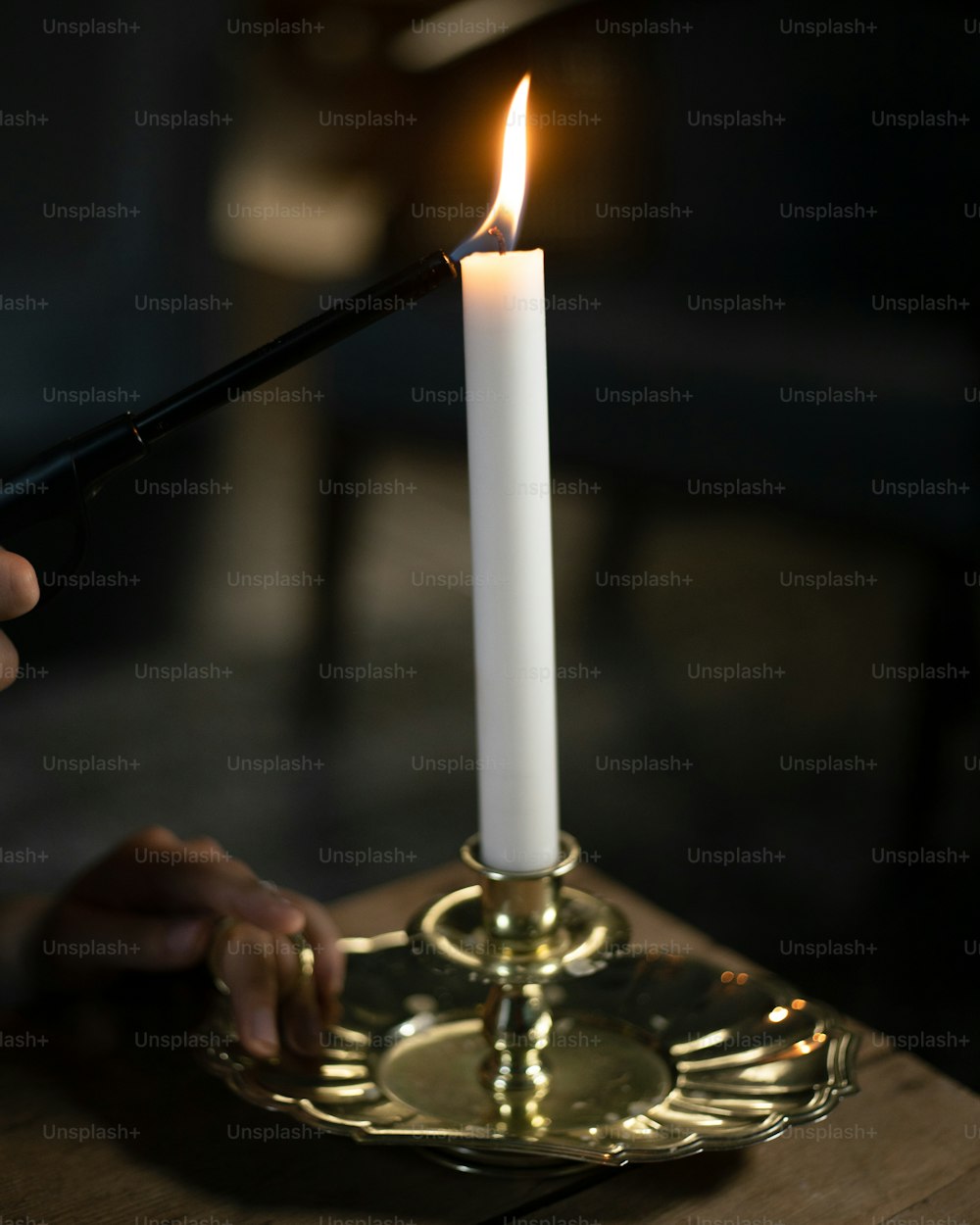 a person lighting a candle on a gold plate