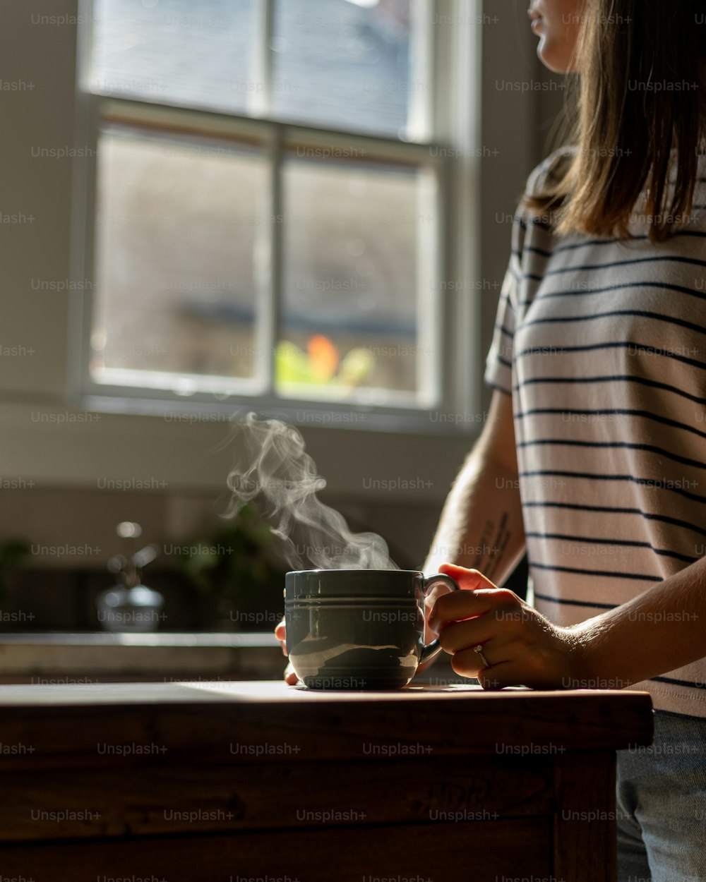Eine Frau, die an einer Küchentheke steht und eine Tasse in der Hand hält