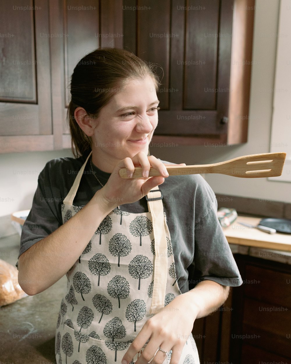 a woman in an apron holding a wooden spatula