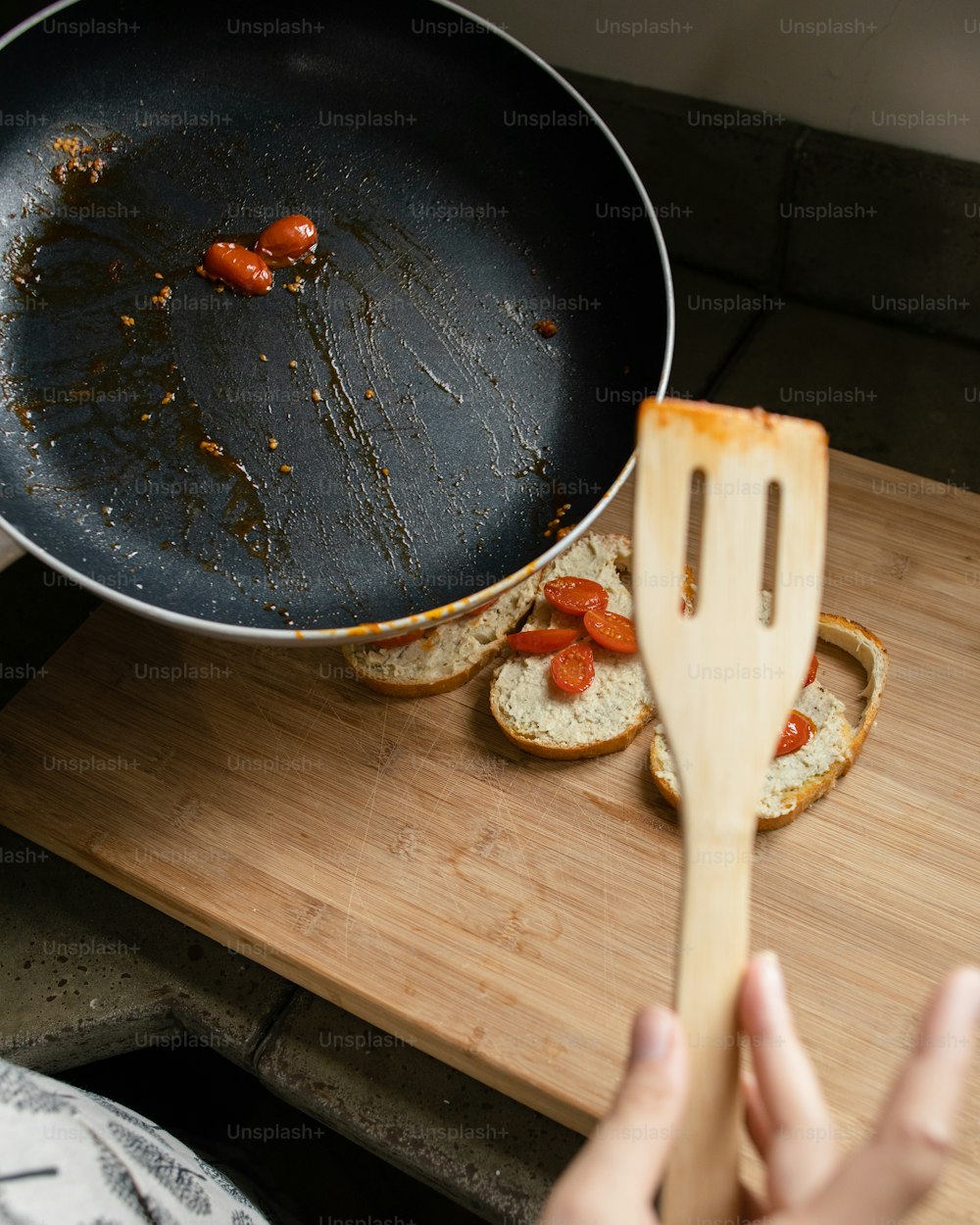 a person holding a wooden spatula in front of a frying pan filled with