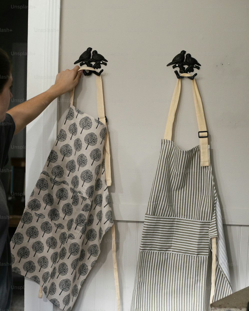 two aprons hanging on a wall next to each other
