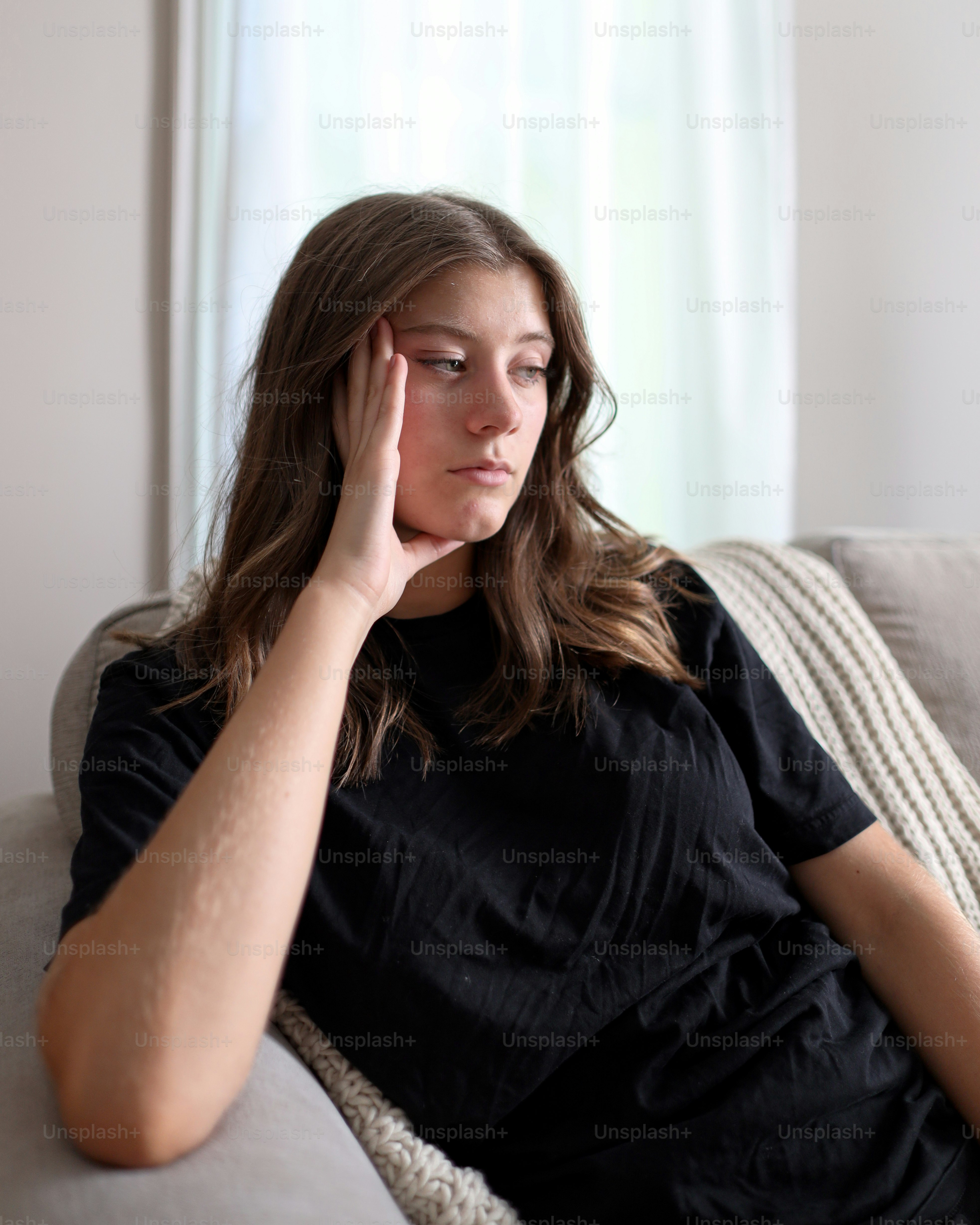 a woman sitting on a couch holding her head