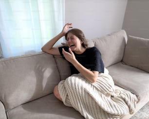 a woman sitting on a couch with her hand on her head