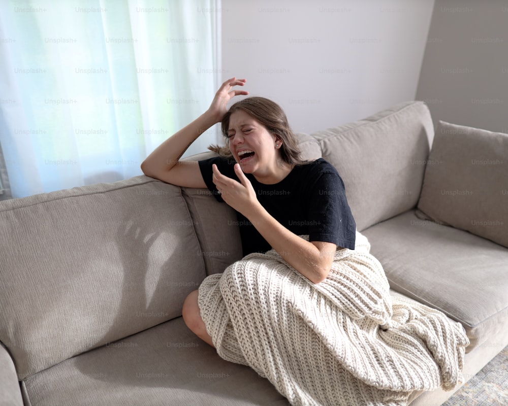 a woman sitting on a couch with her hand on her head