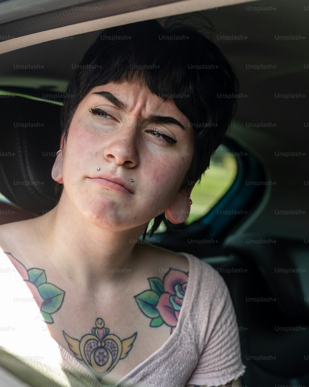 Eine Frau mit einem Tattoo auf der Brust sitzt in einem Auto