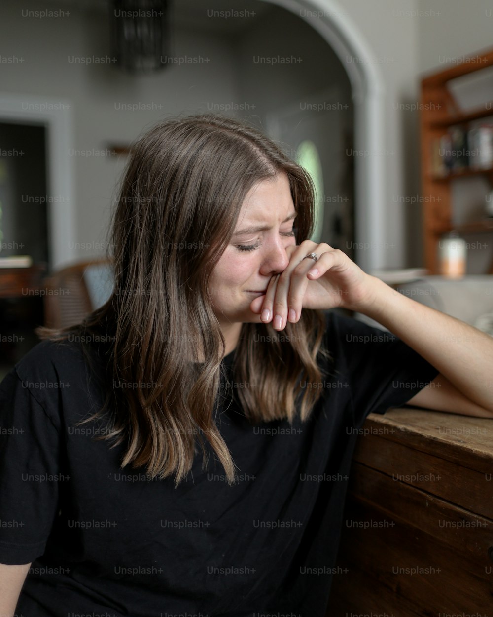 uma mulher sentada em uma mesa com a mão no rosto