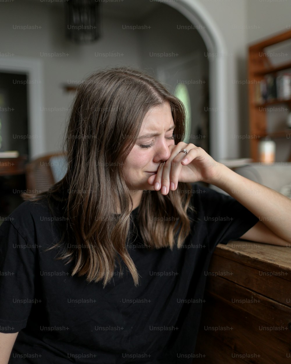 Una mujer sentada en una mesa con la mano en la cara