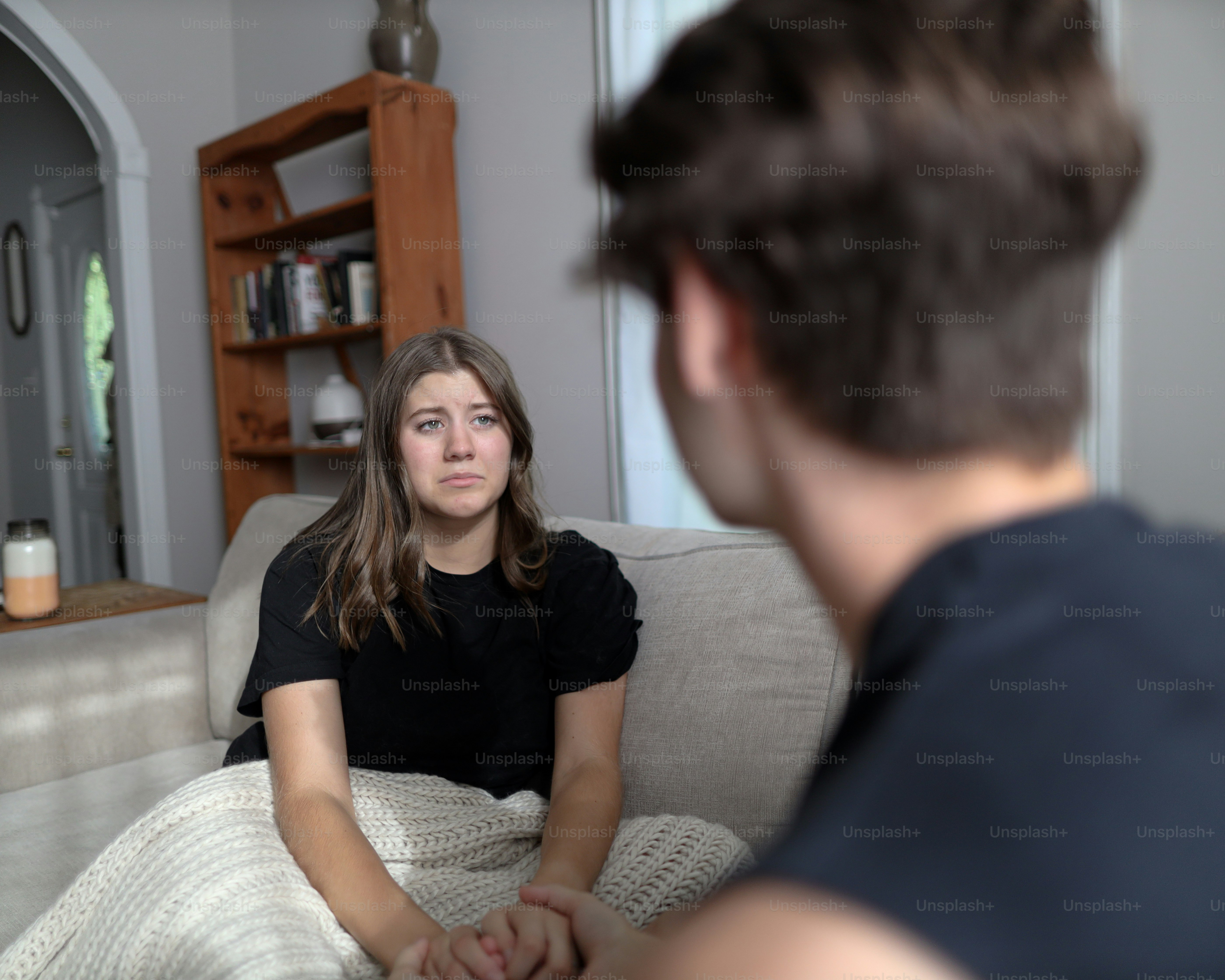 a woman sitting on a couch in front of a man