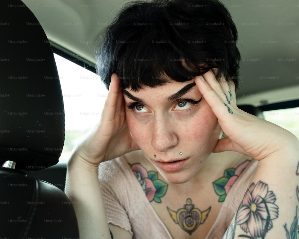 uma mulher com tatuagens sentada em um carro