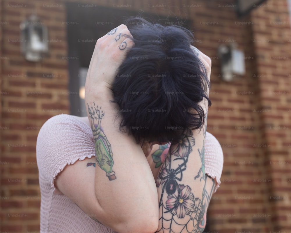 a woman with tattoos covering her face with her hands