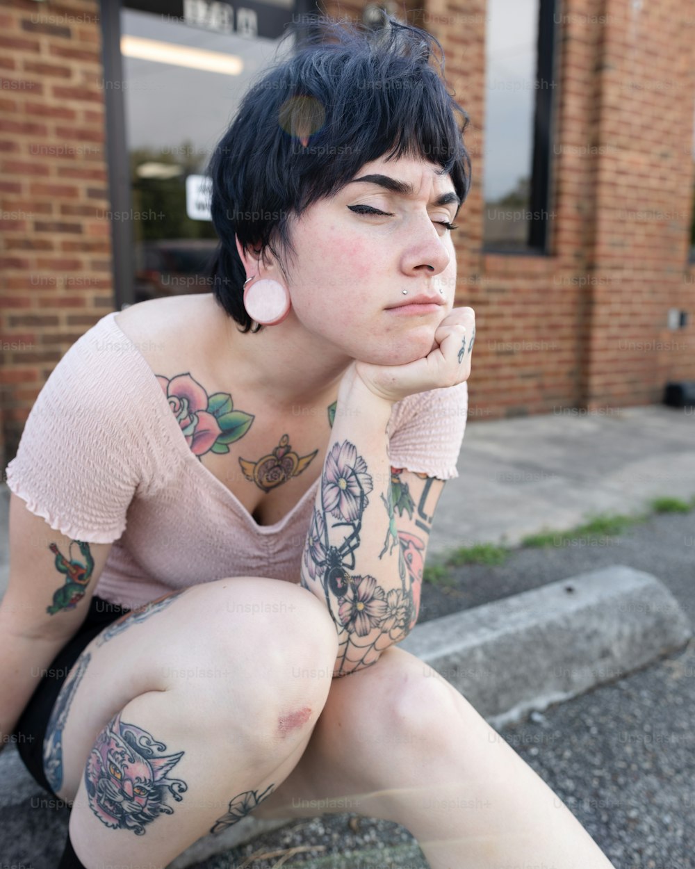 a woman with tattoos sitting on the ground