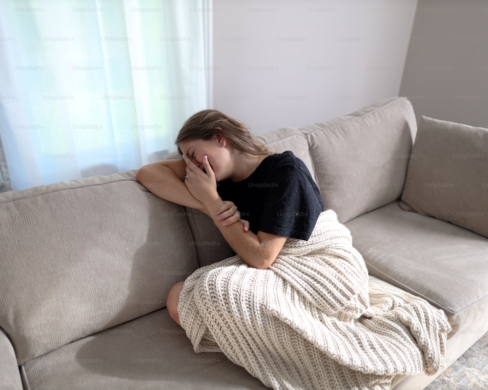 una donna seduta su un divano con la testa sulla mano